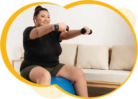 A person with medium-light skin sitting on a blue exercise ball. They are holding dumbbells in their hands, with their arms stretched out in front of them.