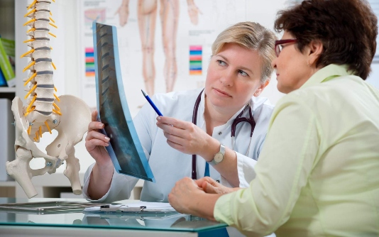 Un médecin regarde une radiographie d'une colonne vertébrale avec un patient