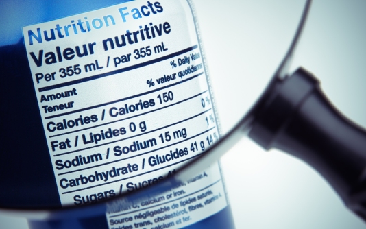 L'étiquette nutritionnelle sur une canette de soda est examinée à la loupe