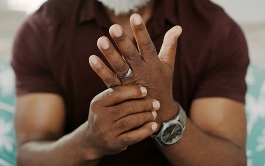 Un homme qui tient sa main endolorie par l'arthrite